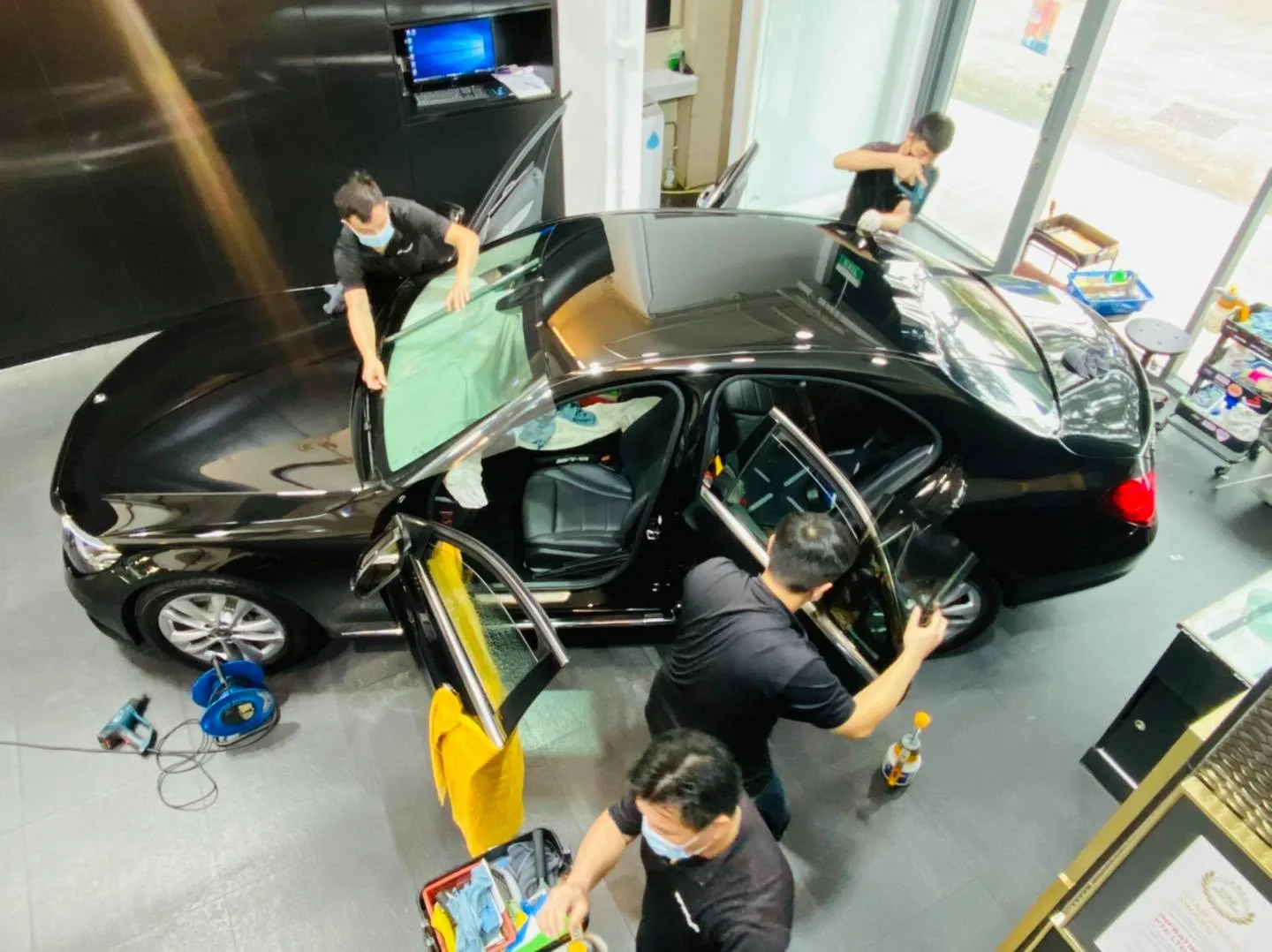 Overhead view of a team tinting a black Mercedes-Benz C-Class at Infratint Singapore