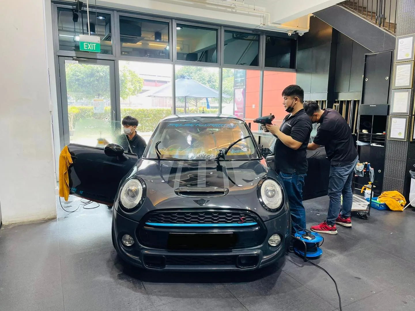 Installers tinting a black Mini Cooper at Infratint Singapore