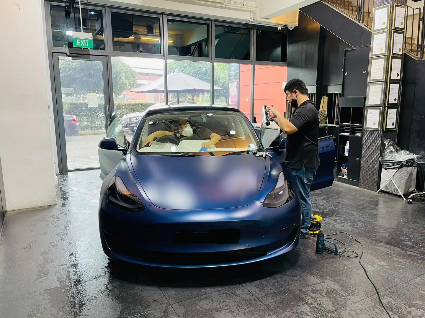 Installer working on a matte blue Tesla Model 3 windscreen at Infratint Singapore