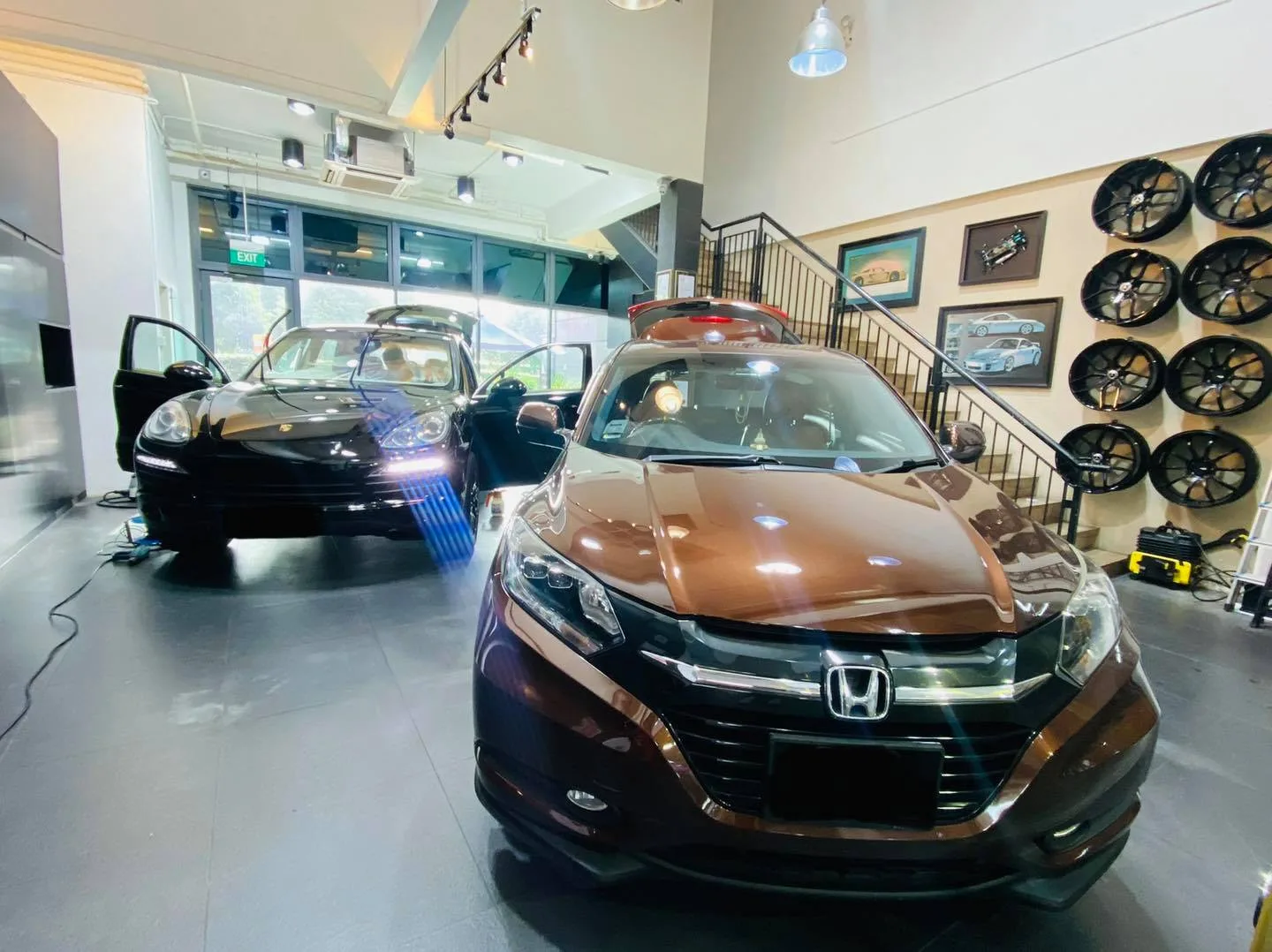 Brown Honda crossover and black Porsche Cayenne inside the Infratint Singapore showroom