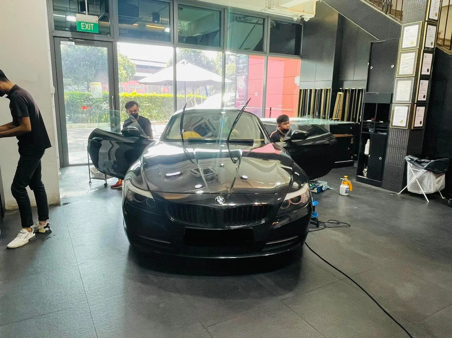 Black BMW roadster being window tinted by two installers at Infratint Singapore