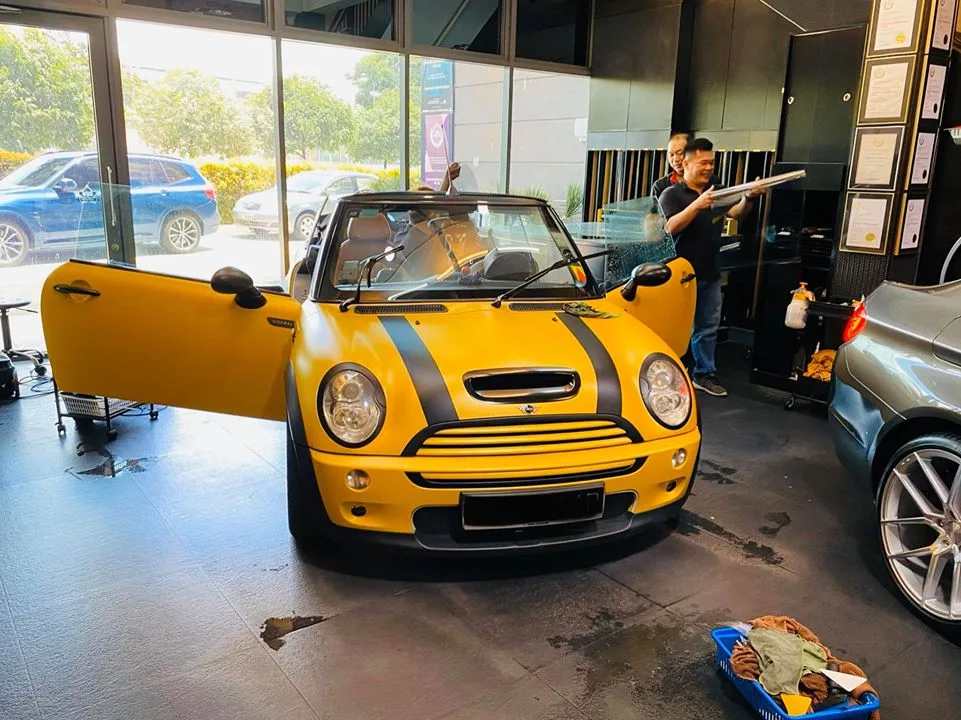 Yellow Mini Cooper convertible with door open being prepared for window tinting at Infratint Singapore