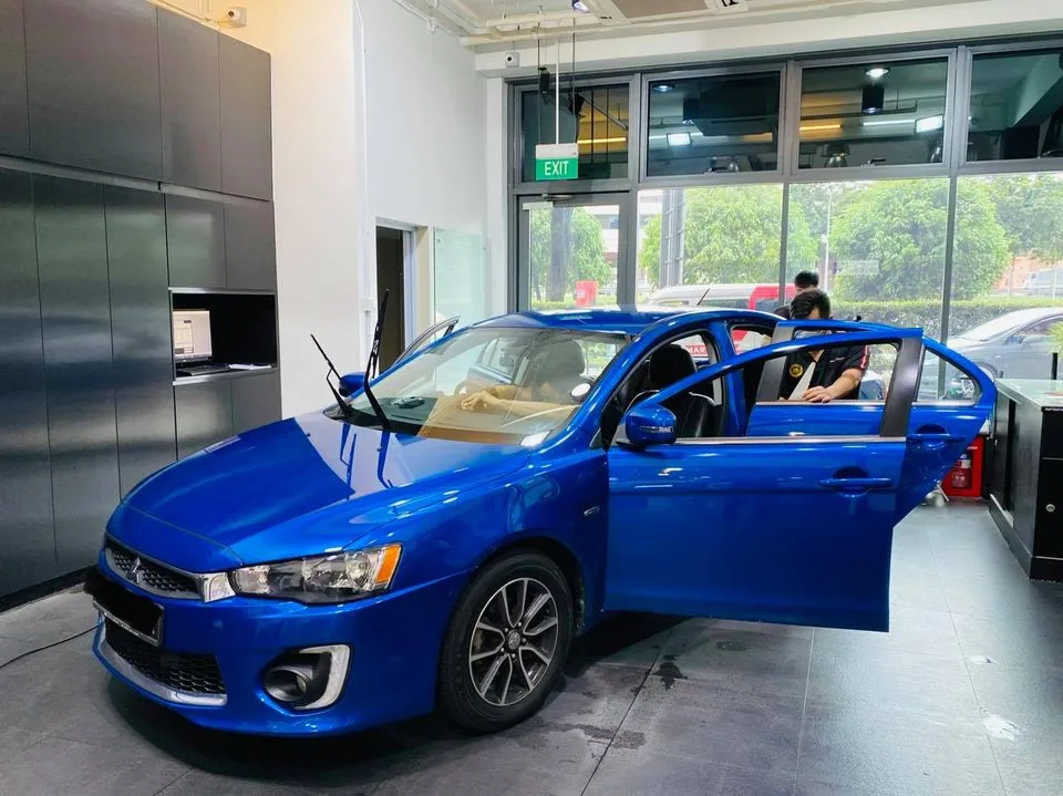 Blue Mitsubishi Lancer with doors open during window tinting at Infratint Singapore