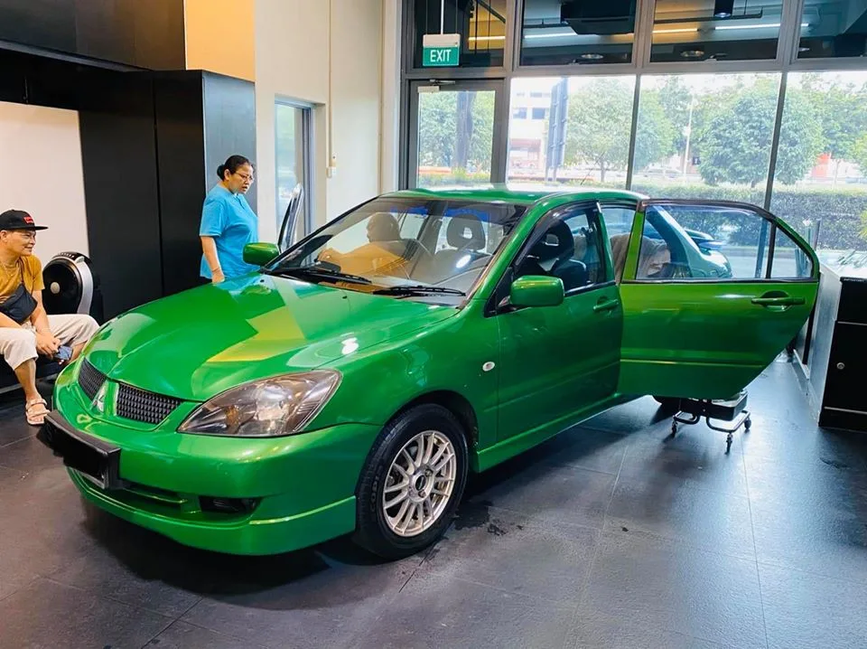 Green Mitsubishi Lancer front three-quarter with doors open inside Infratint Singapore workshop