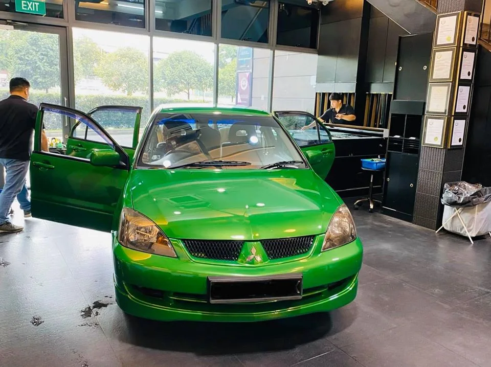 Green Mitsubishi Lancer front view inside Infratint Singapore workshop during film install