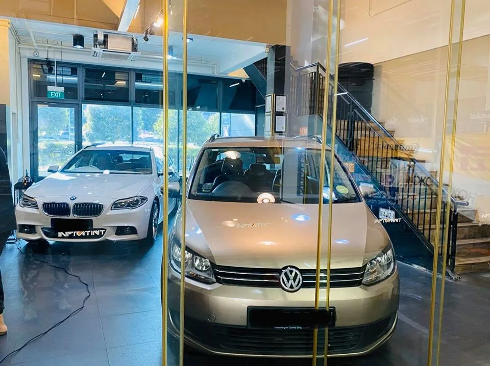Gold Volkswagen MPV and white BMW behind a glass partition at Infratint Singapore