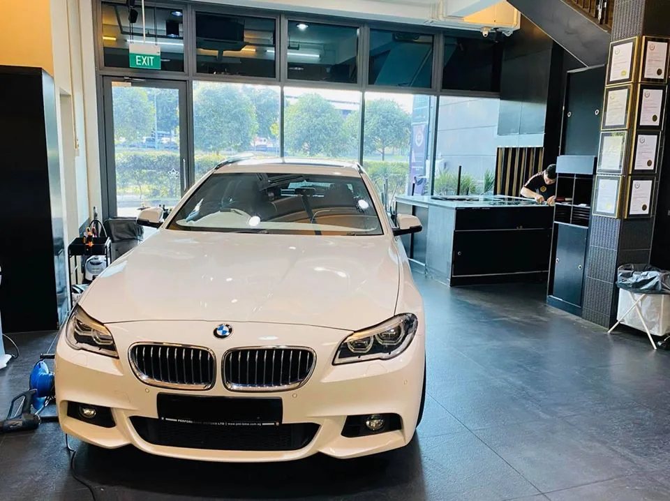 White BMW 5 Series sedan inside the Infratint Singapore showroom in the morning