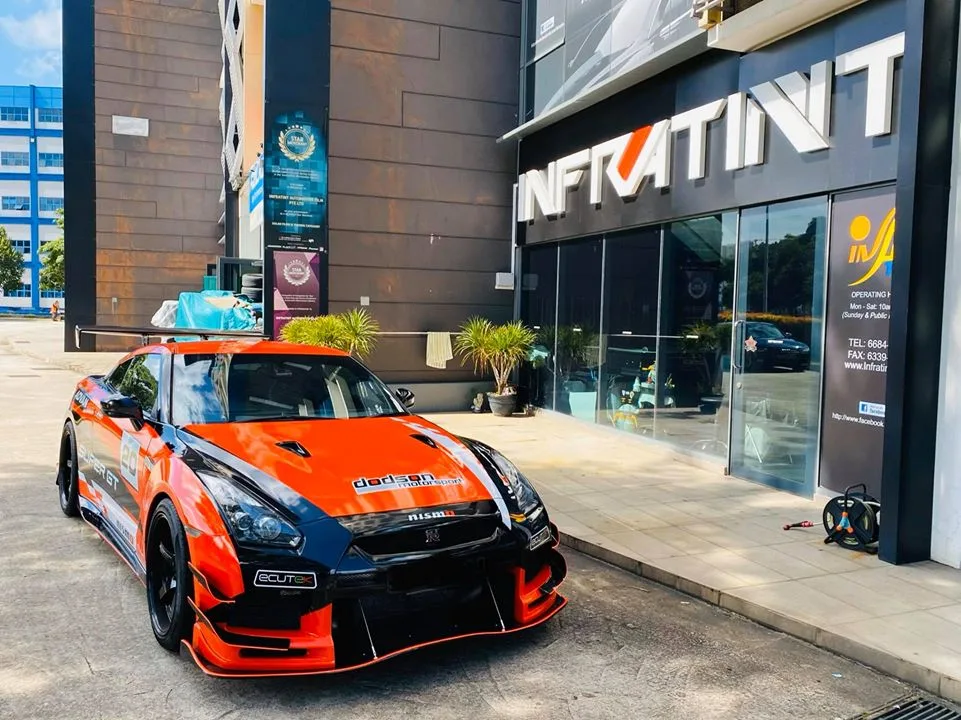 Orange wide-body Nissan GT-R parked in front of the Infratint Singapore storefront