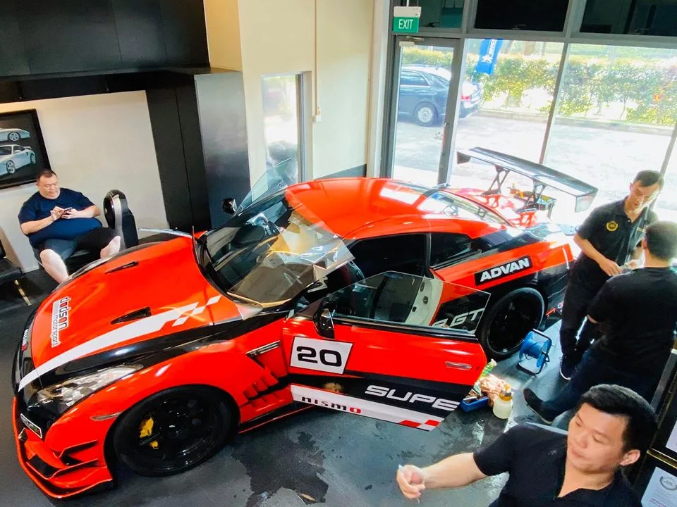 Overhead view of an orange number 20 Nissan GT-R inside the Infratint Singapore install bay