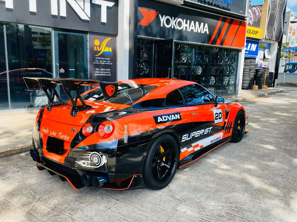 Orange Nissan GT-R rear three-quarter with race wing outside Infratint Singapore