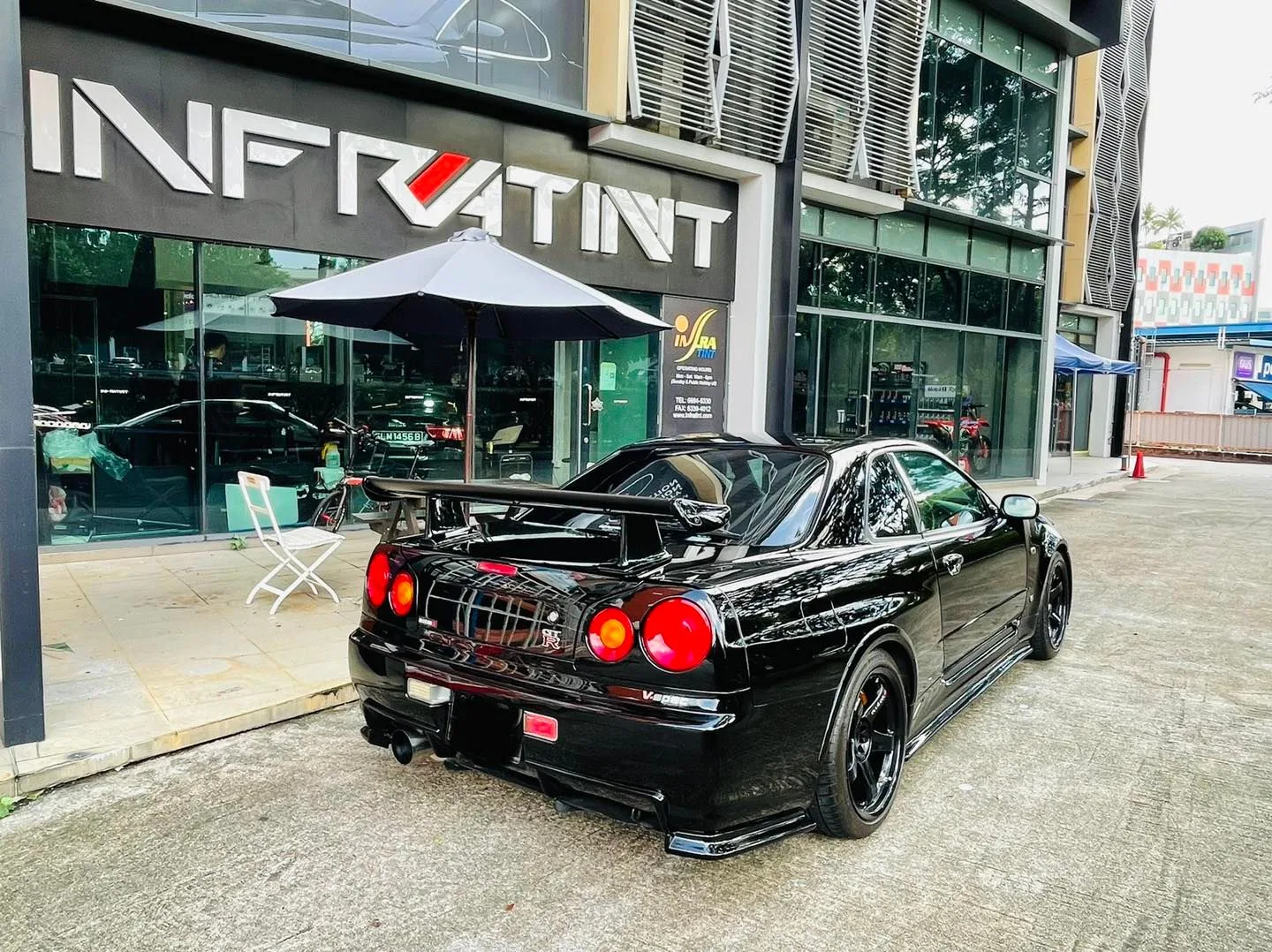Black Nissan GT-R R34 rear view with wing and round taillights at Infratint Singapore