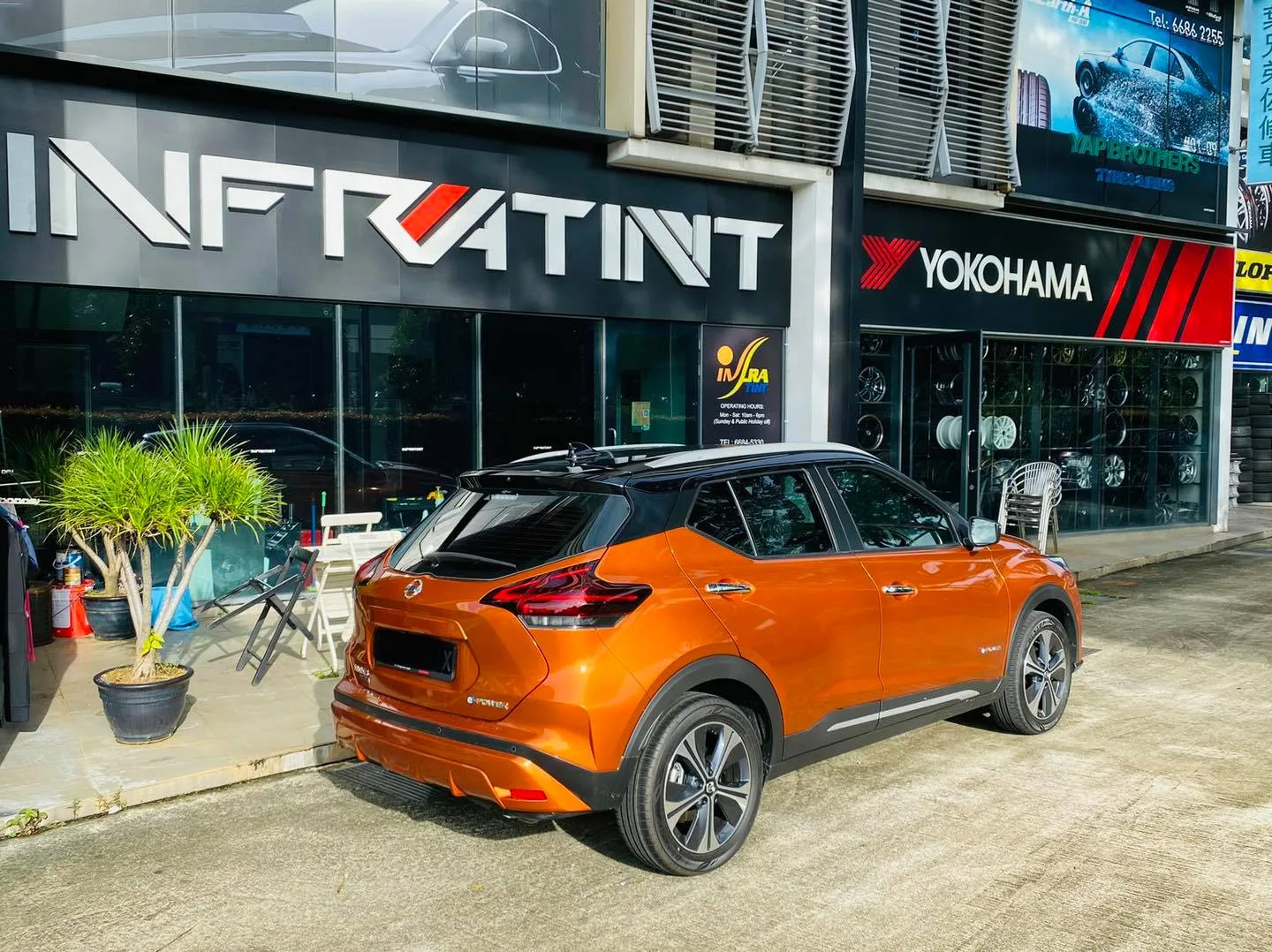 Orange Nissan Kicks rear view with tinted windows outside Infratint Singapore