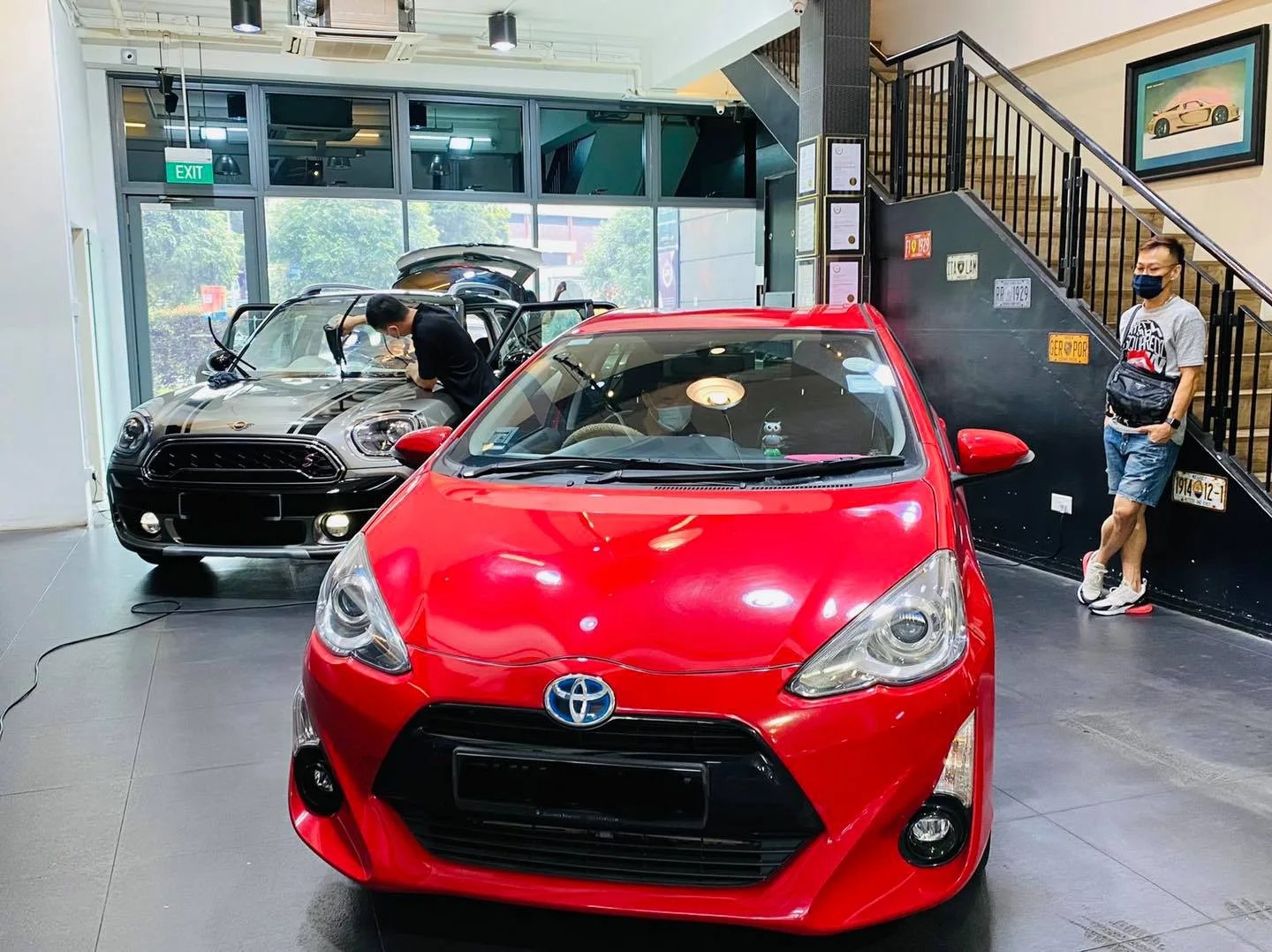 Red Toyota hatchback and grey Mini Countryman inside the Infratint Singapore showroom