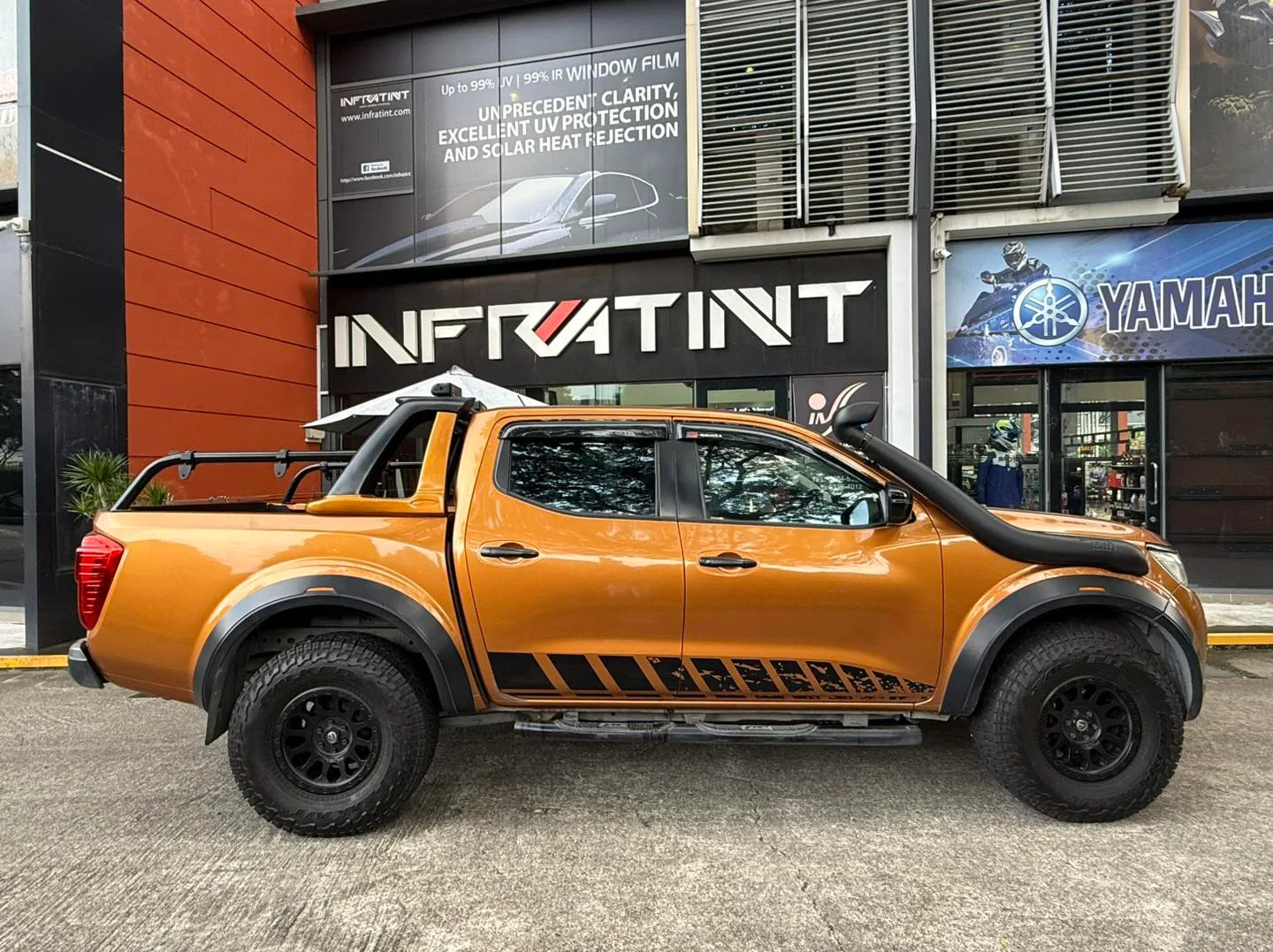 Orange Nissan Navara side profile with tinted windows at Infratint Singapore