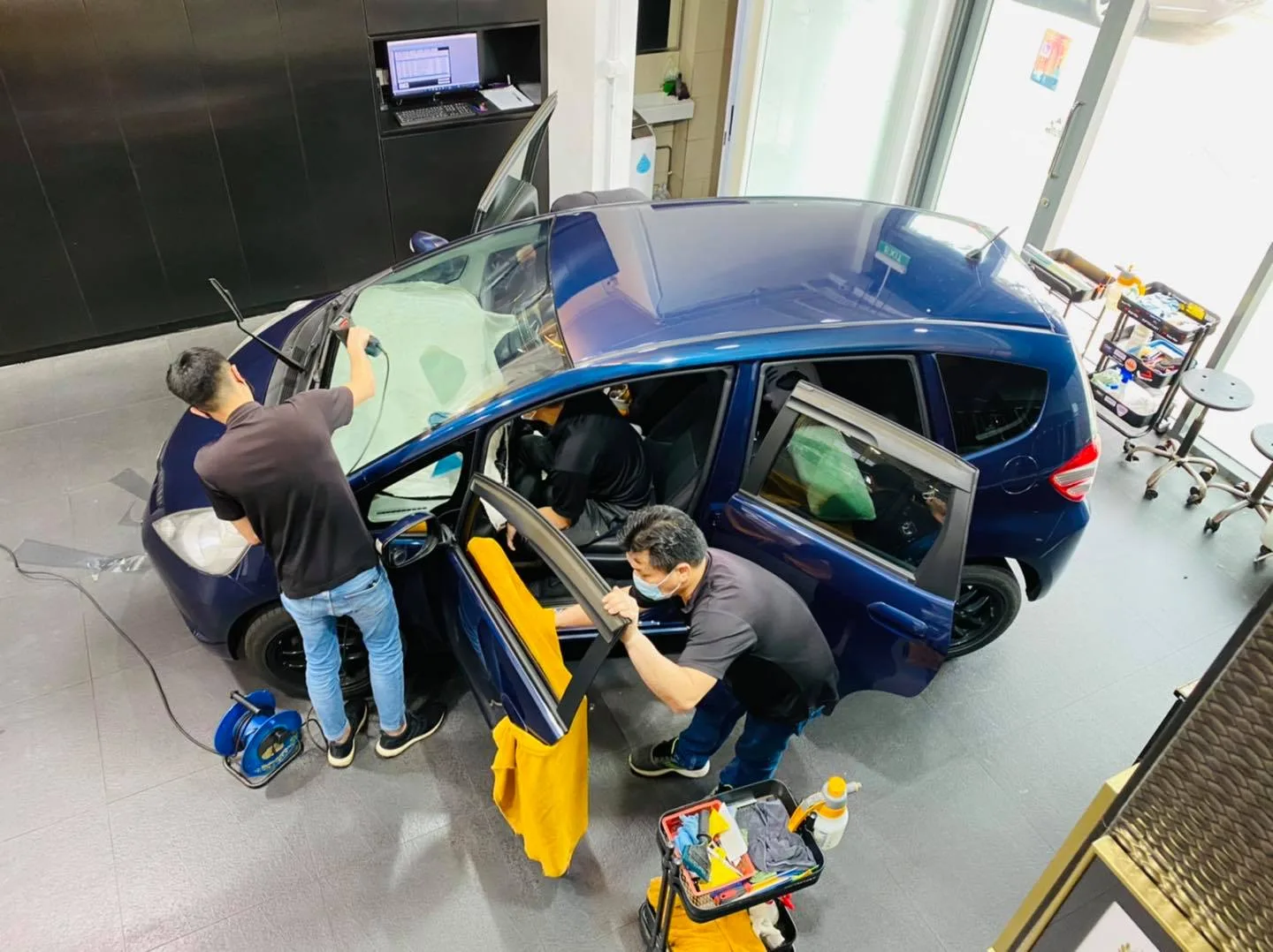 Overhead view of two technicians tinting a blue Honda hatchback at Infratint Singapore