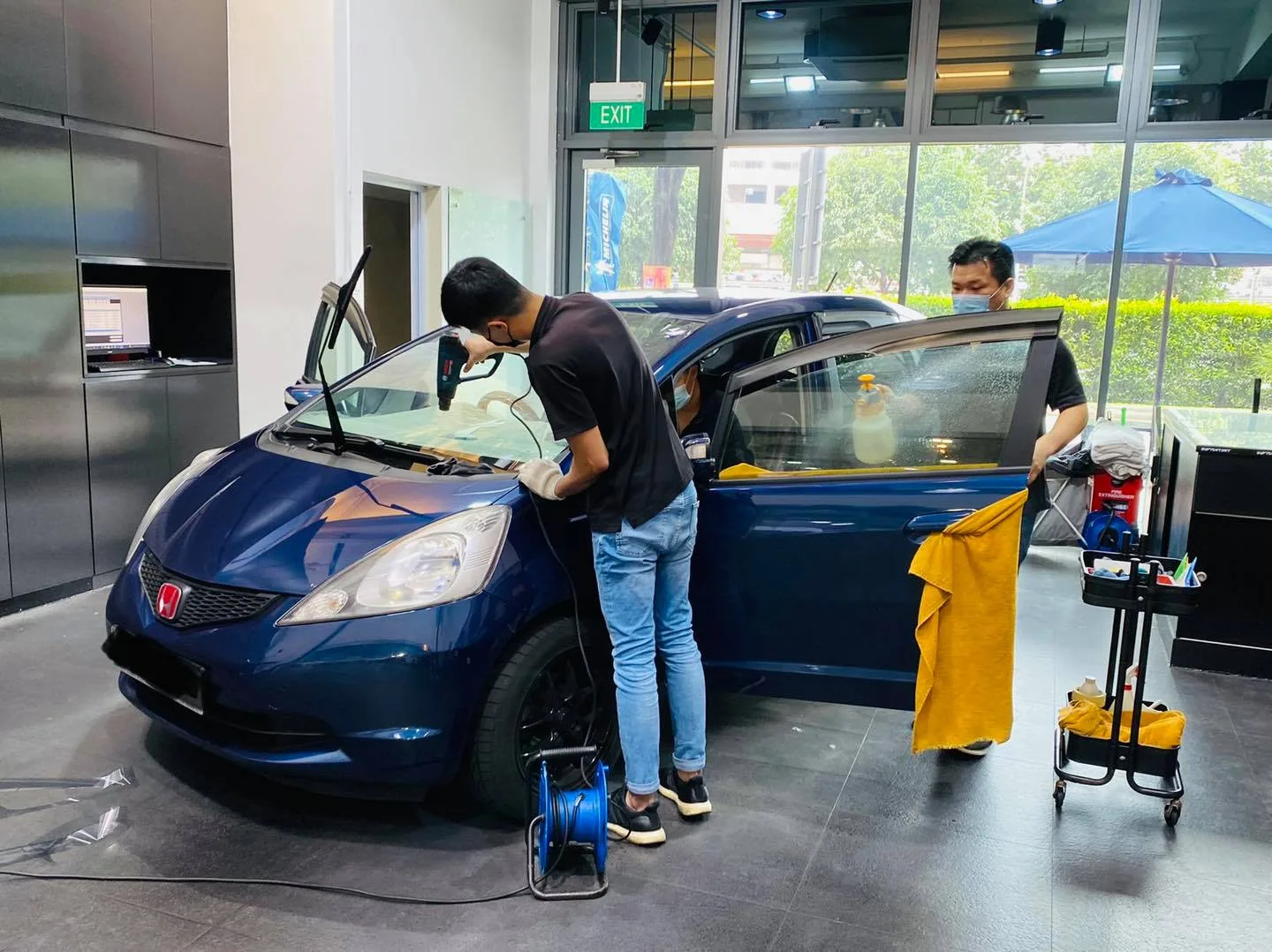Blue Honda hatchback with door open during window film installation at Infratint Singapore