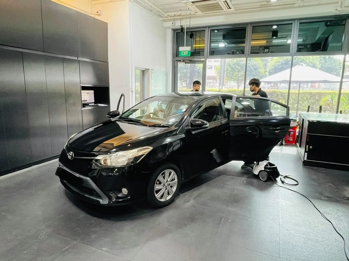 Black Toyota sedan front three-quarter during window film install at Infratint Singapore