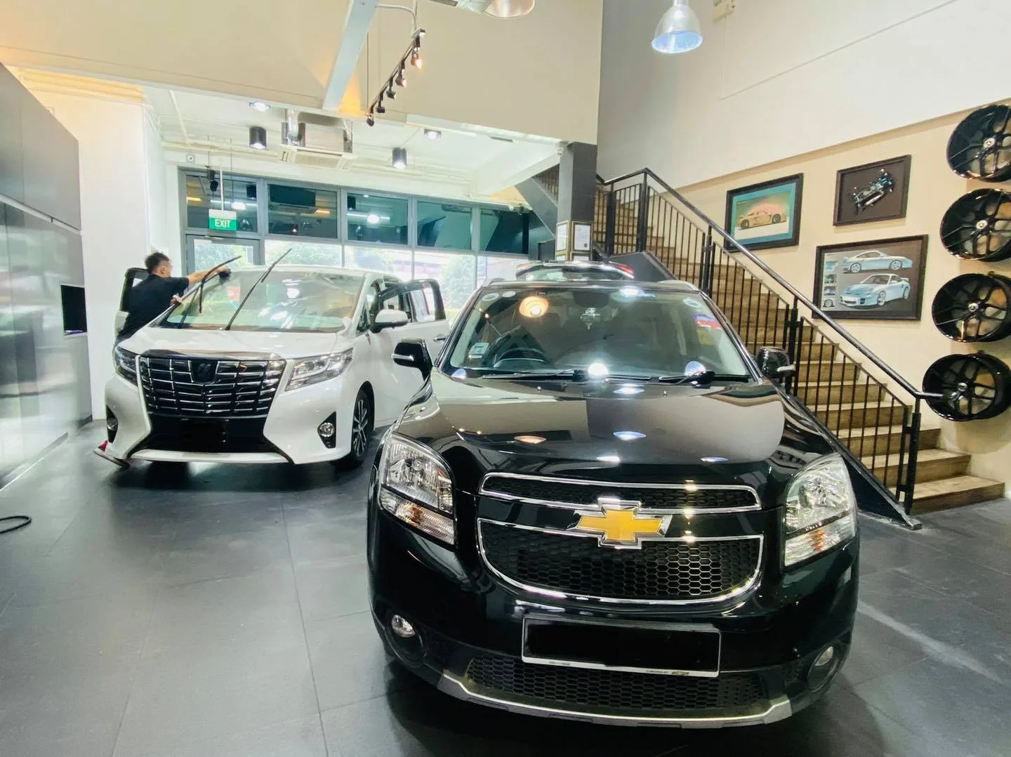 Black Chevrolet SUV and white Toyota Alphard inside the Infratint Singapore showroom