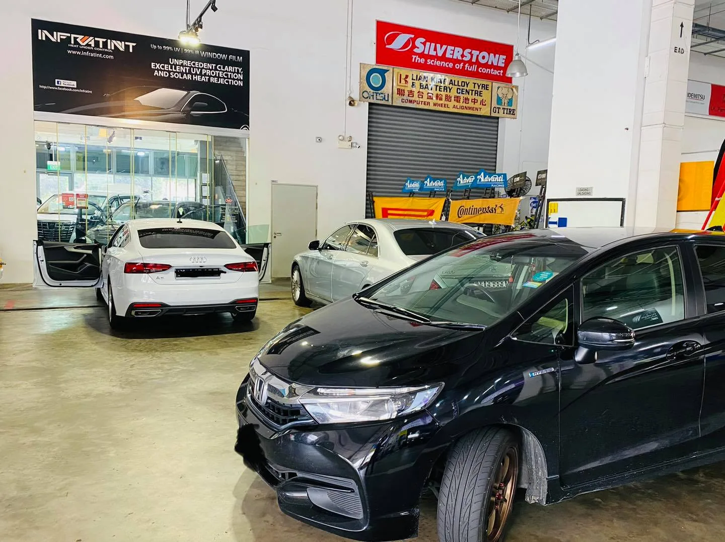 Black Honda Fit and white Audi sedan under the Infratint banner at Infratint Singapore