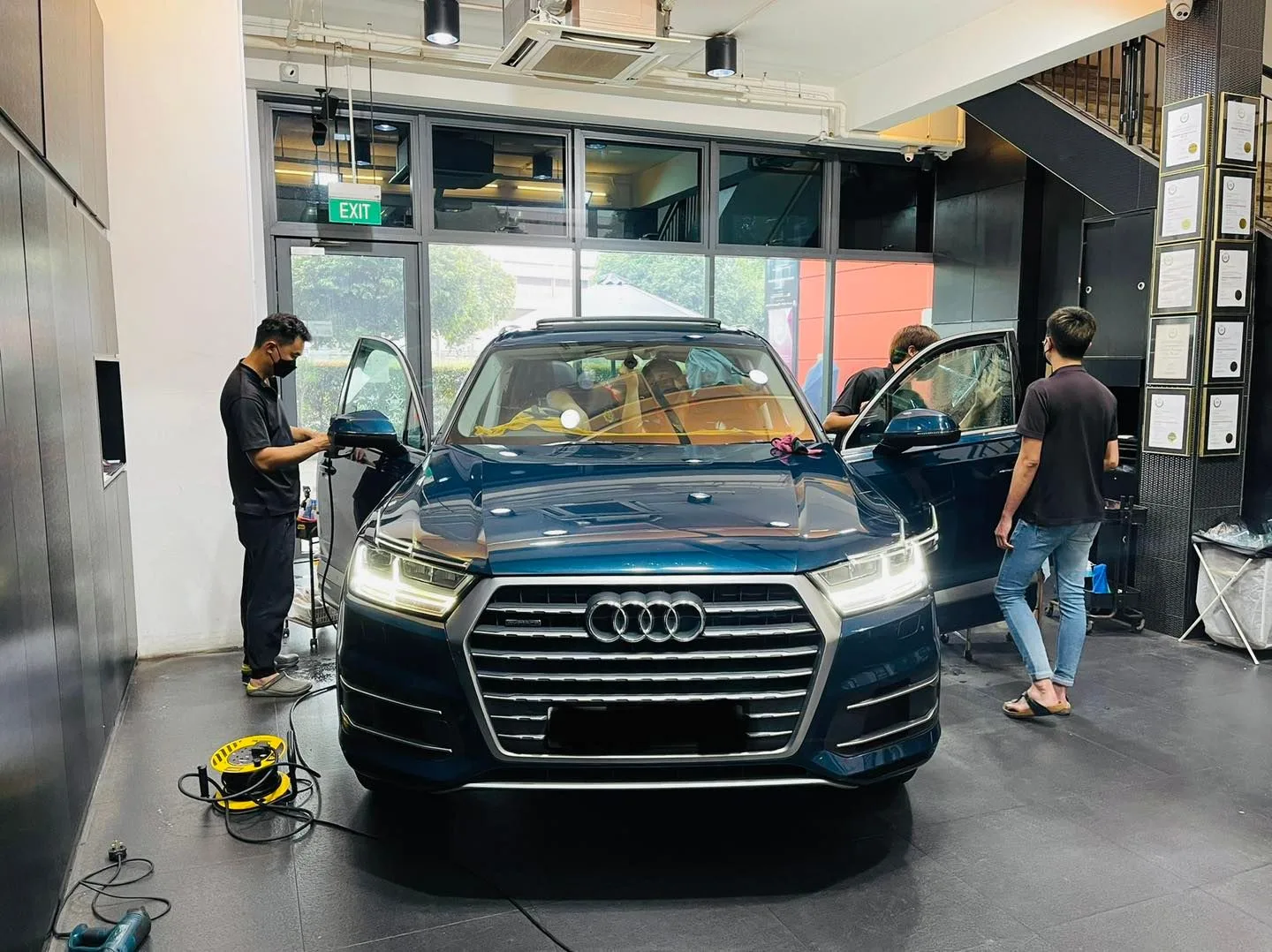 Dark blue Audi SUV being tinted by two technicians at Infratint Singapore