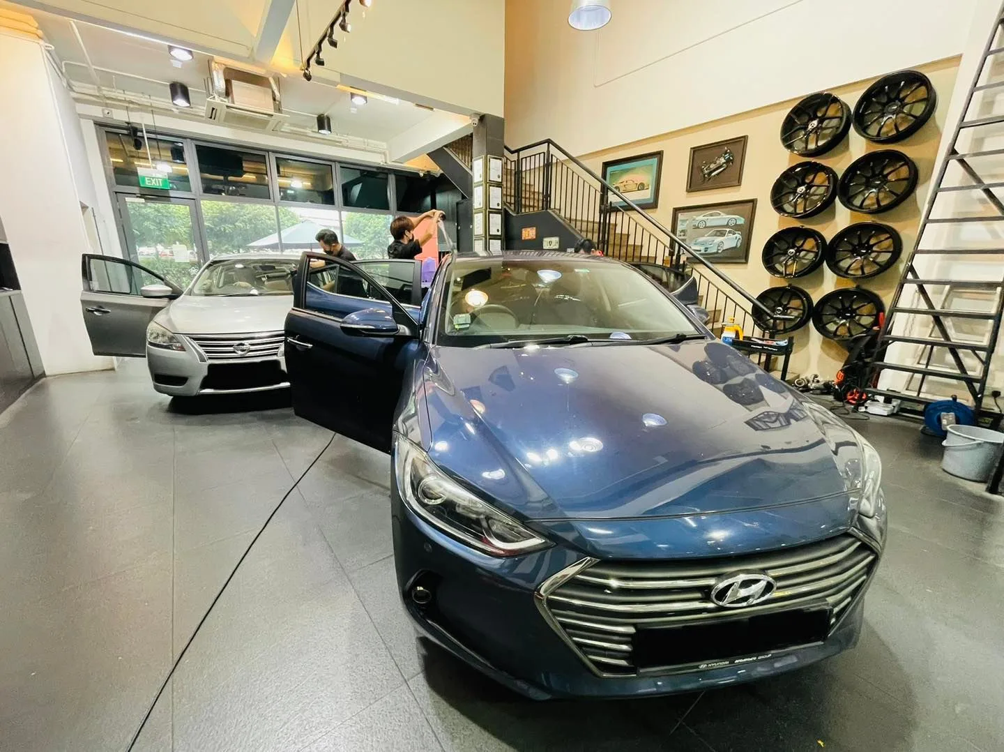 Blue Hyundai sedan and silver Honda inside Infratint Singapore for window tinting