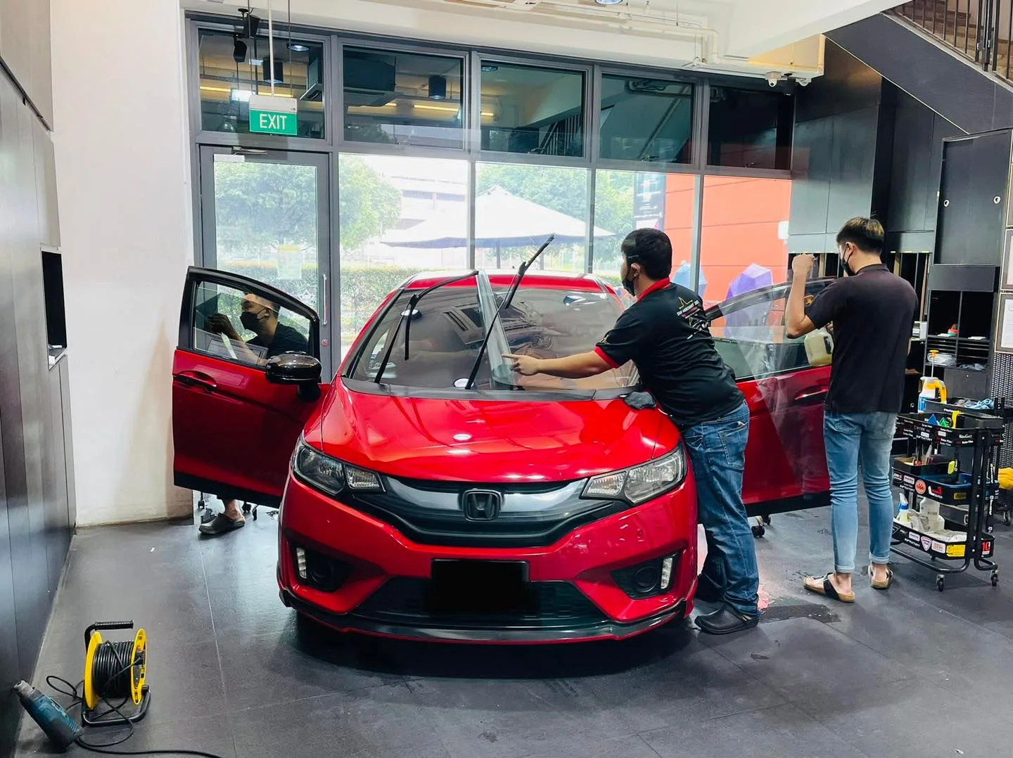 Red Honda Fit hatchback during window film installation at Infratint Singapore