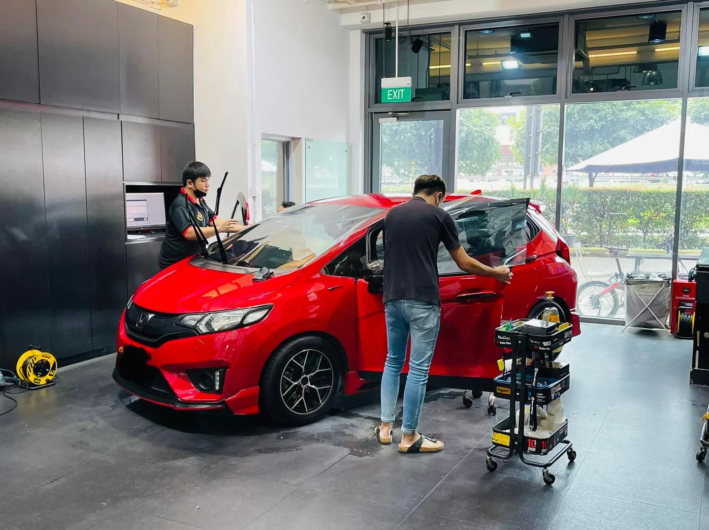 Red Honda Fit having its side window tinted at Infratint Singapore