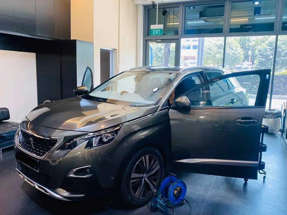 Front three-quarter of a grey Peugeot 3008 SUV with doors open during tinting at Infratint Singapore