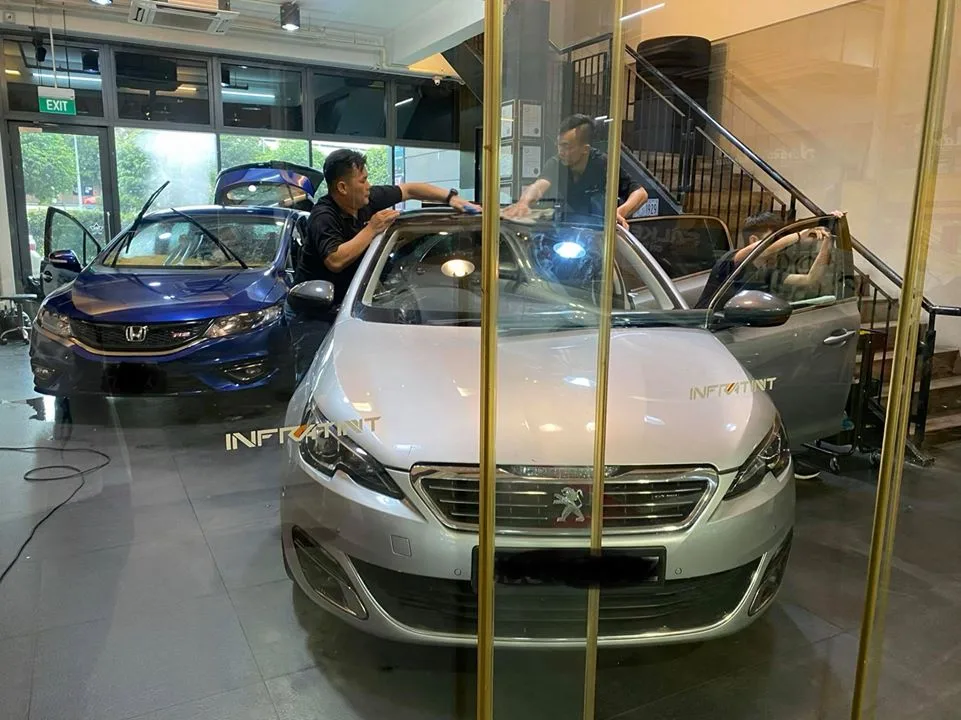 Silver Peugeot 308 and a blue Honda sedan inside Infratint Singapore for window tinting
