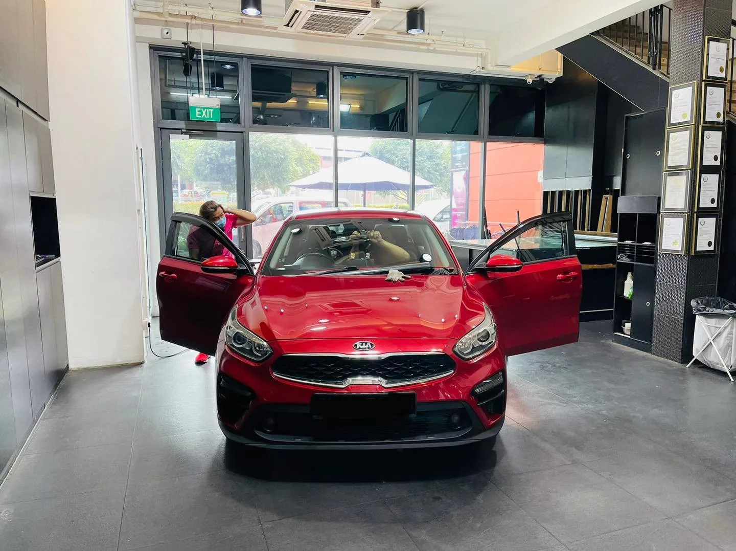 Red Kia sedan with doors open during window tinting at Infratint Singapore