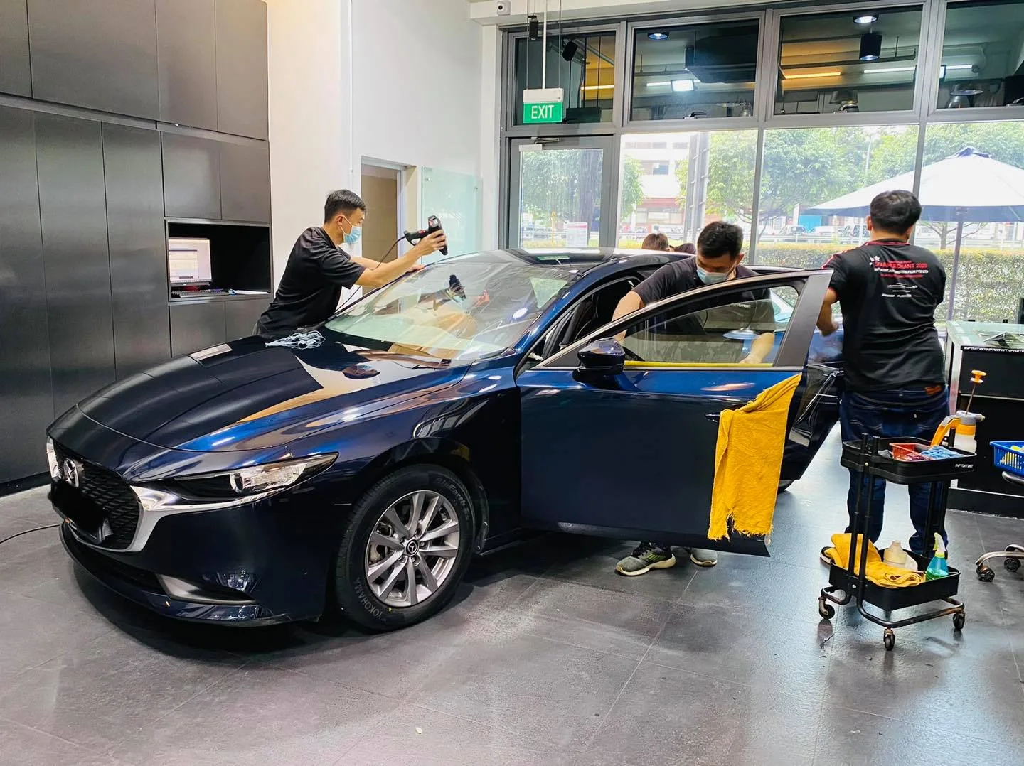 Dark blue Mazda 3 sedan during window film installation at Infratint Singapore