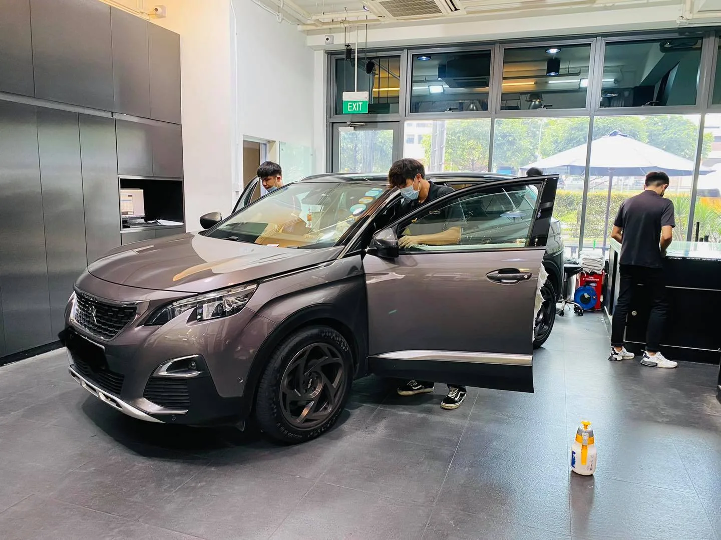 Grey Peugeot 5008 SUV being window tinted by technicians at Infratint Singapore