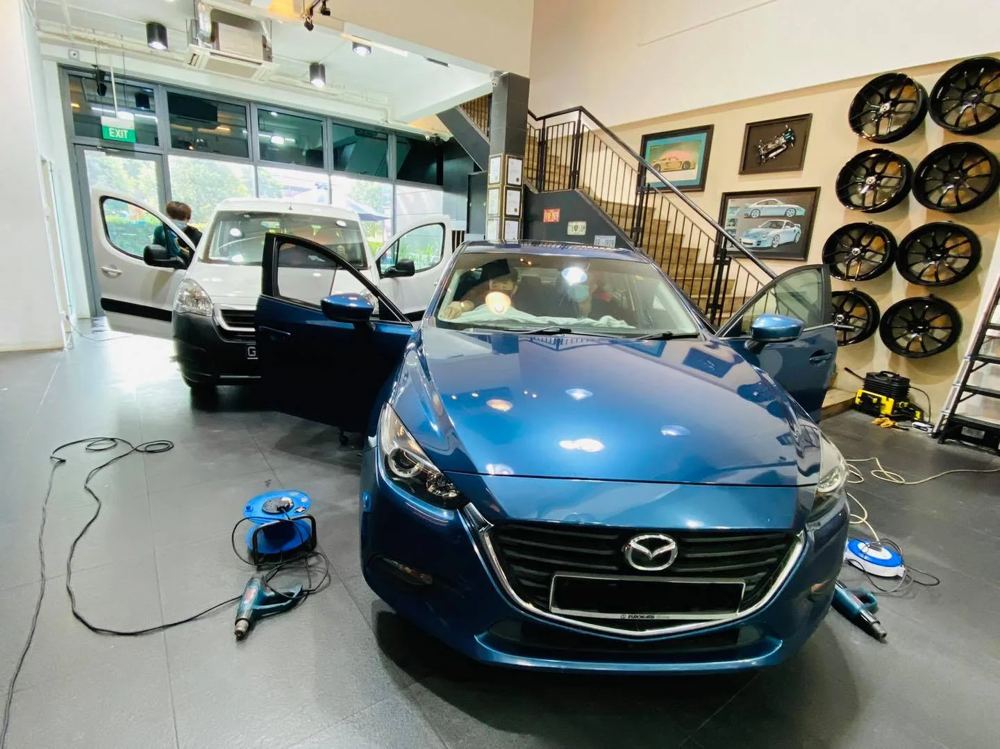 Blue Mazda 3 during window tinting beside a white van at Infratint Singapore