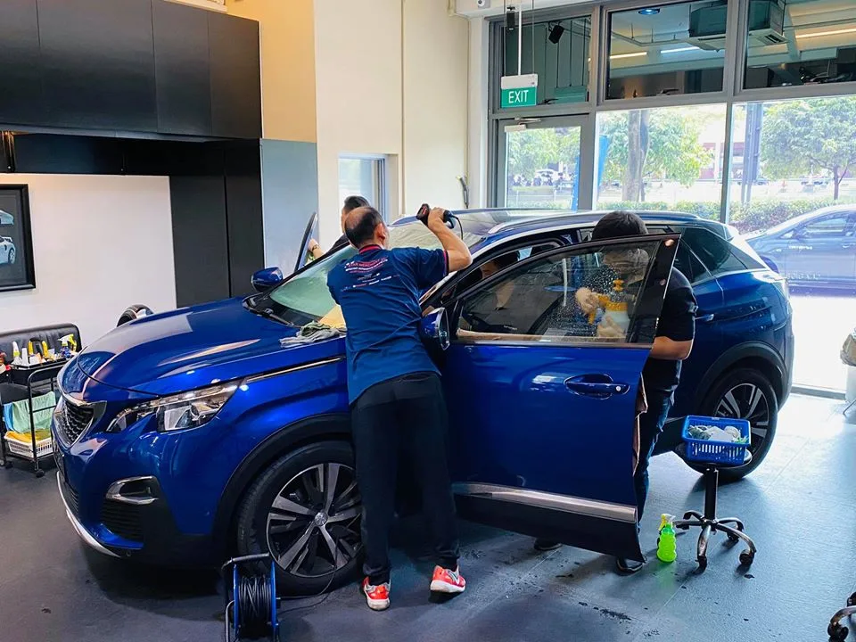Technician installing window film on the door glass of a blue Peugeot SUV at Infratint Singapore