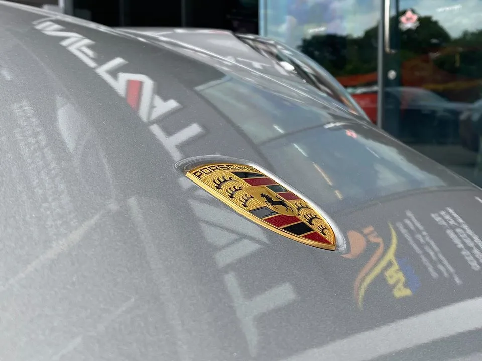Close-up of the Porsche crest on a silver 911 bonnet at Infratint Singapore