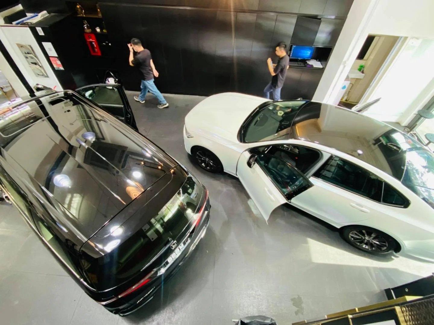 Overhead view of a black Honda and a white sedan inside the Infratint Singapore showroom