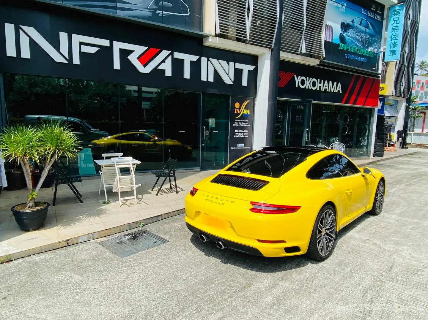 Yellow Porsche 911 rear view at the Infratint Singapore storefront