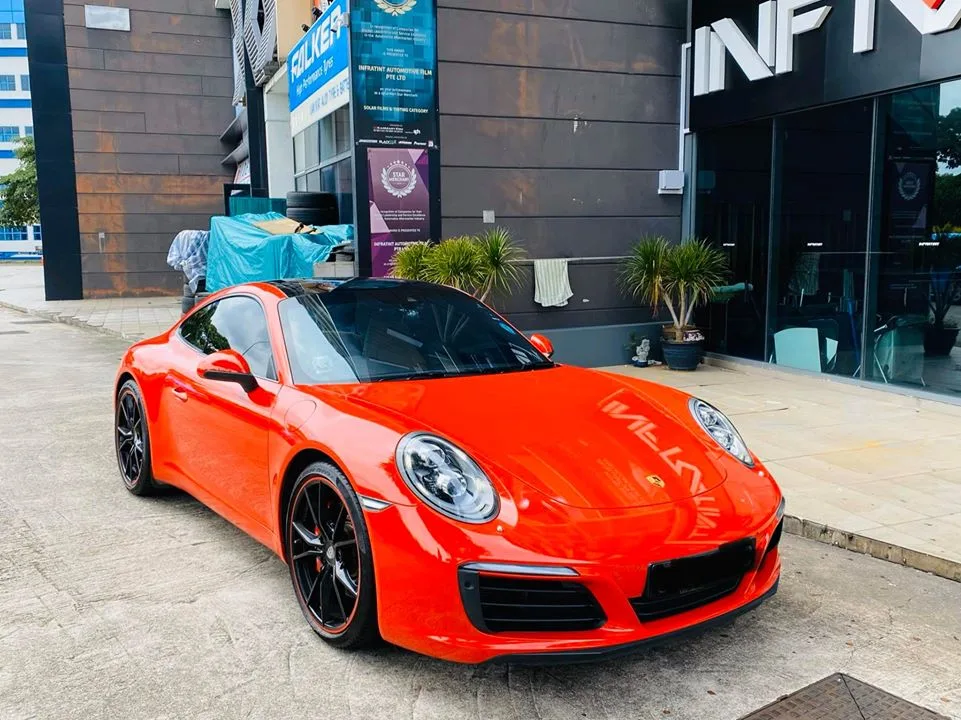 Lava orange Porsche 911 parked outside Infratint Singapore after window tinting