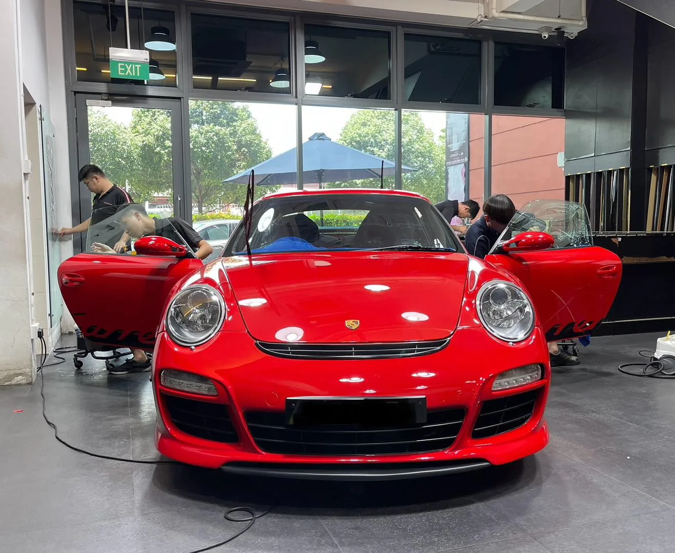 Technicians installing window film on a red Porsche 911 inside the Infratint workshop