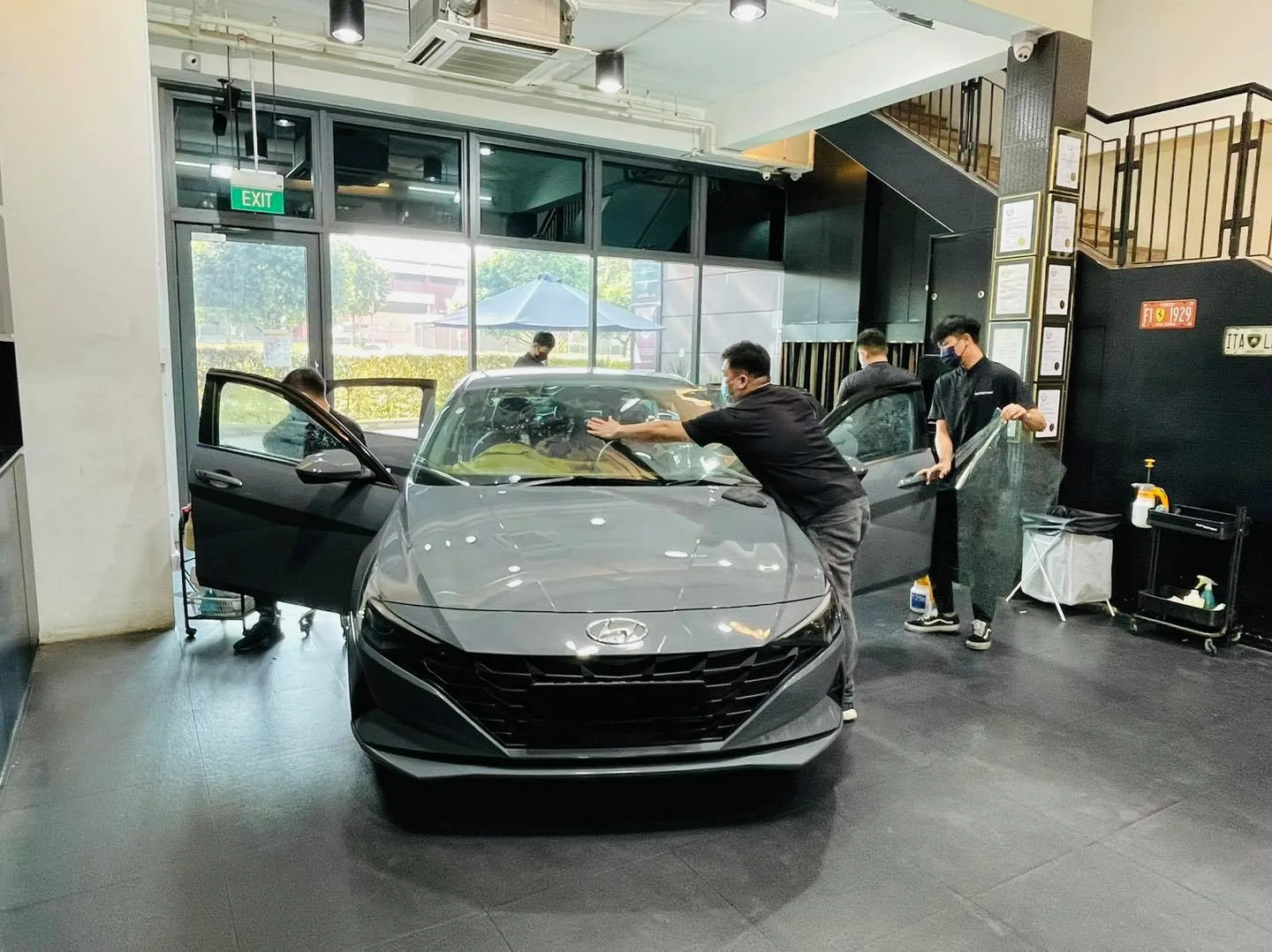 Two installers tinting a grey Hyundai Avante with doors open at Infratint Singapore