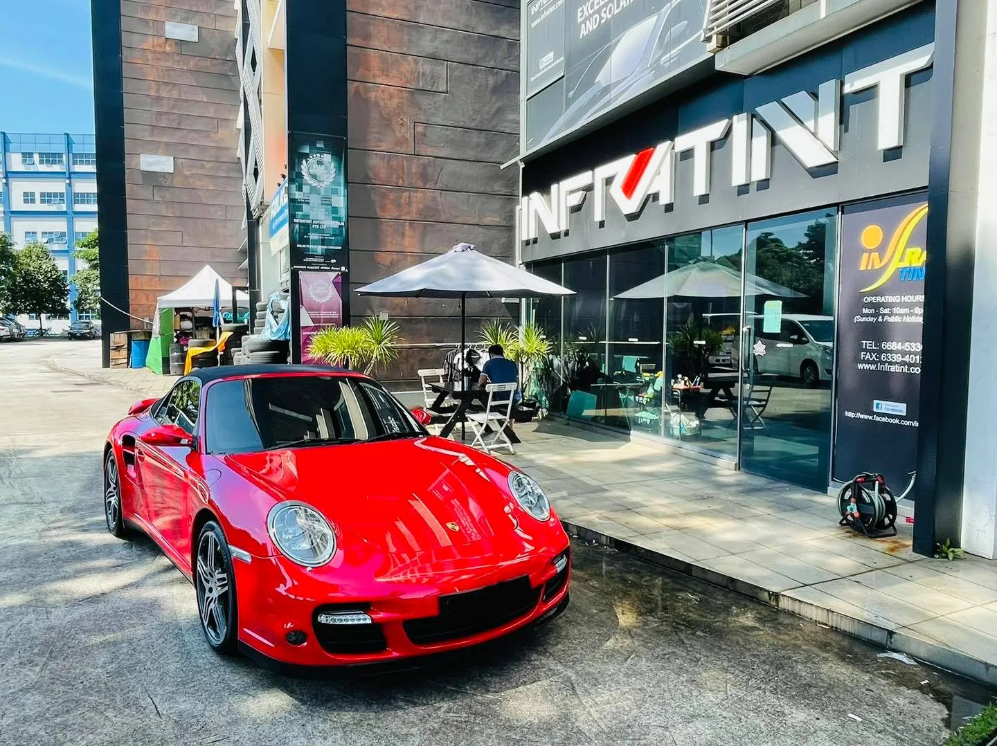 Red Porsche 911 Turbo cabriolet parked outside the Infratint Singapore shopfront