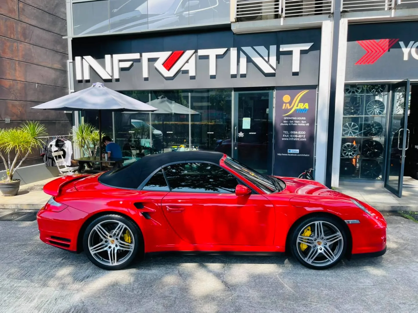 Side profile of a red Porsche 911 Turbo cabriolet outside Infratint Singapore