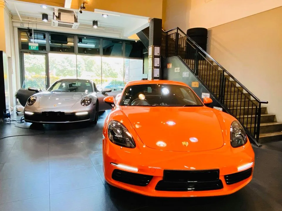 Orange Porsche 718 and silver Porsche 911 inside the Infratint Singapore showroom
