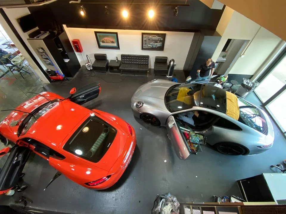 Overhead view of a red Porsche 718 and silver 911 being tinted at Infratint Singapore
