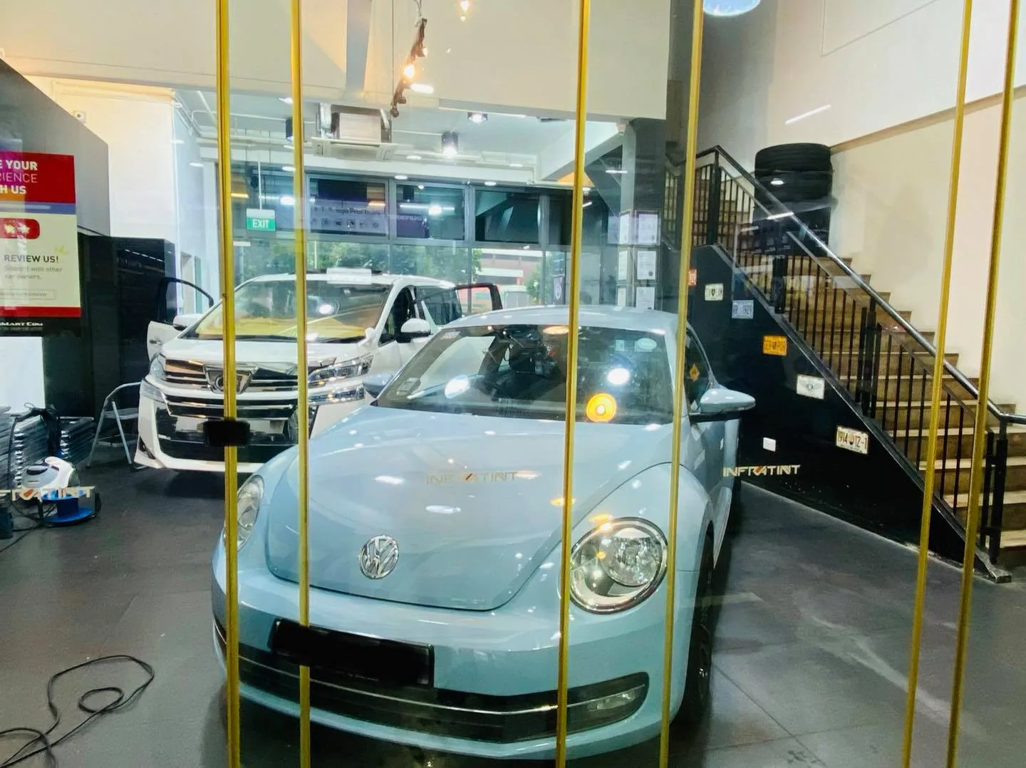 Light blue Volkswagen Beetle and white Toyota Vellfire inside Infratint Singapore for window tinting