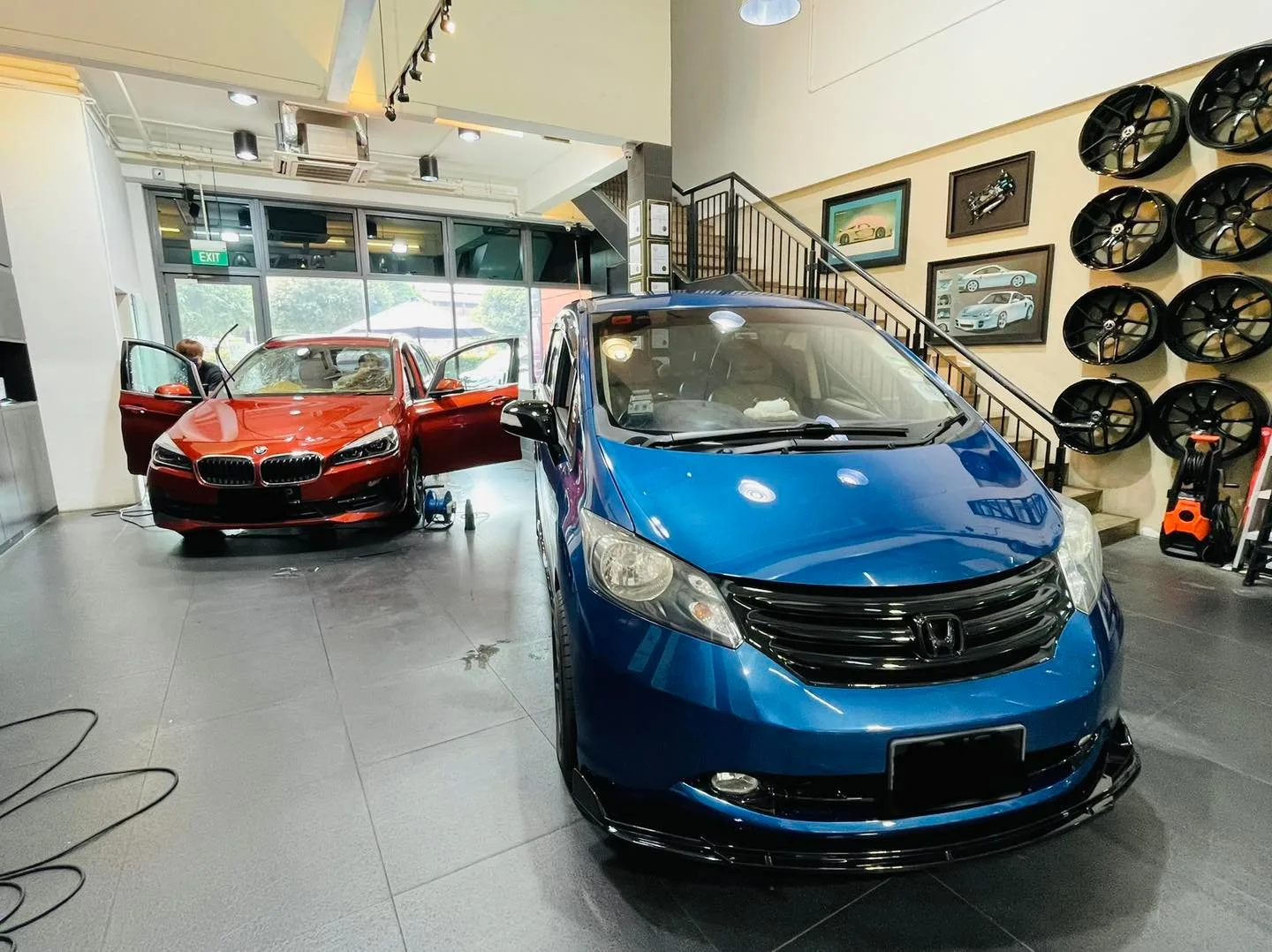 Blue Honda Freed and orange BMW in the Infratint Singapore showroom for window film