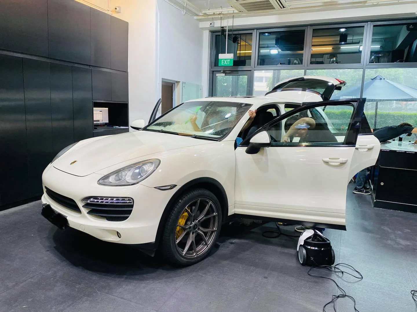 White Porsche Cayenne front three-quarter view during window film install at Infratint Singapore