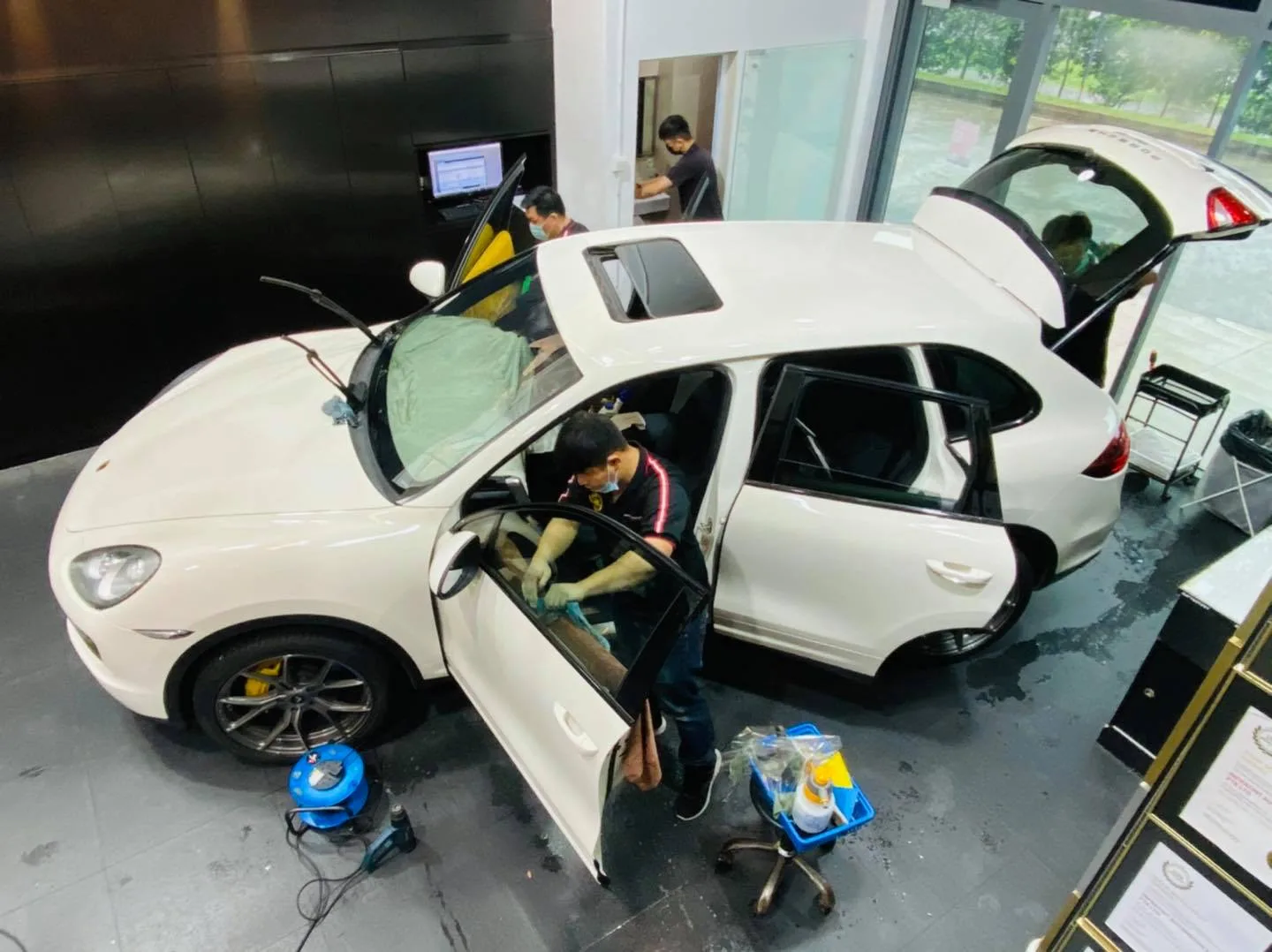 Installer applying window film to a white Porsche Cayenne seen from above at Infratint Singapore