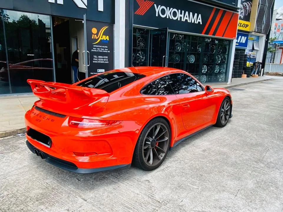 Rear three-quarter of an orange Porsche 911 GT3 outside Infratint Singapore