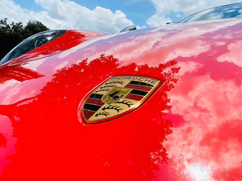 Close-up of the Porsche crest on an orange GT3 bonnet at Infratint Singapore